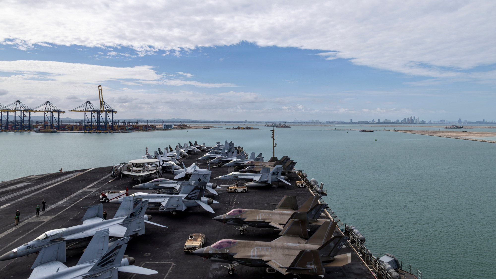 The USS Abraham Lincoln at Laem Chabang, its flight deck lined with F/A-18s and F-35s, the Thai coast behind